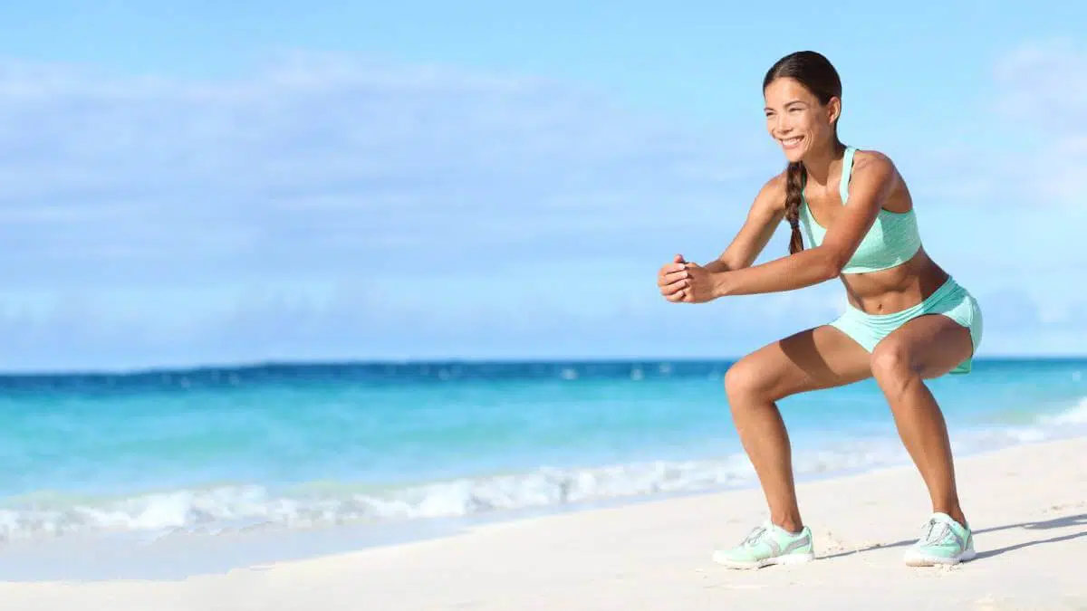 Mujer joven deportistas realizando ejercicio en la arena de playa paradisiaca
